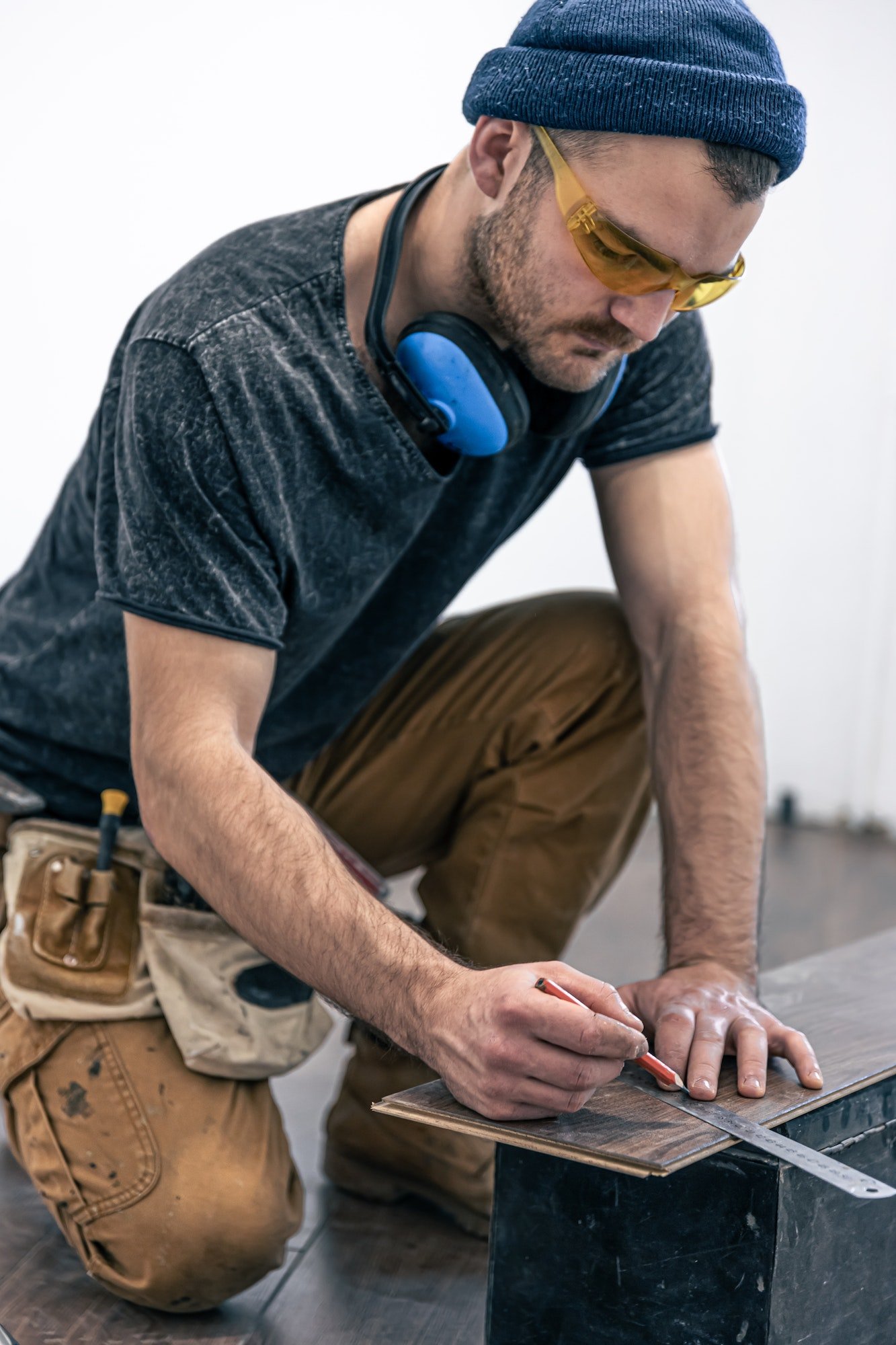 About Us | A male worker puts laminate flooring on the floor.